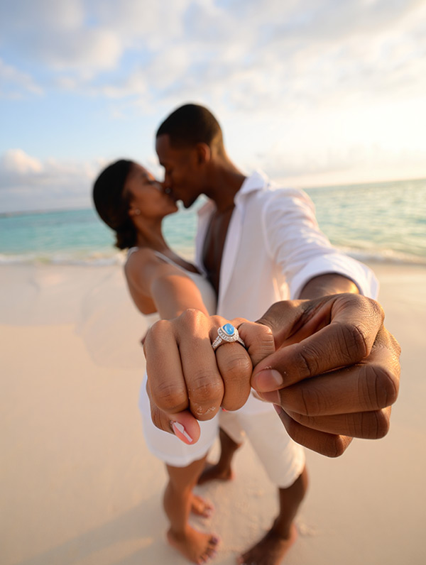 Romantischer Moment - Ein frisch verlobtes Paar am Strand von Sansibar zeigt stolz den Verlobungsring nach einem Überraschungsantrag.