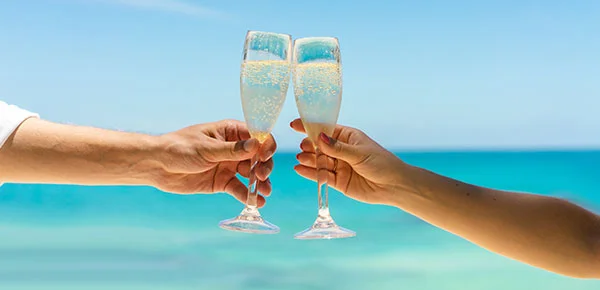A happy couple celebrating their destination wedding in Zanzibar with champagne glasses.