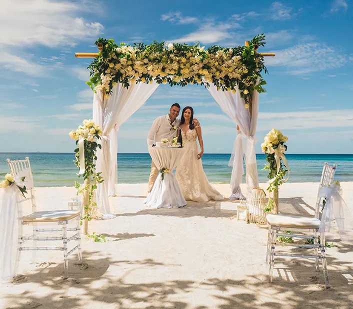 Un couple de jeunes mariés heureux sous un pavillon décoré sur la plage de Kendwa, à Zanzibar.