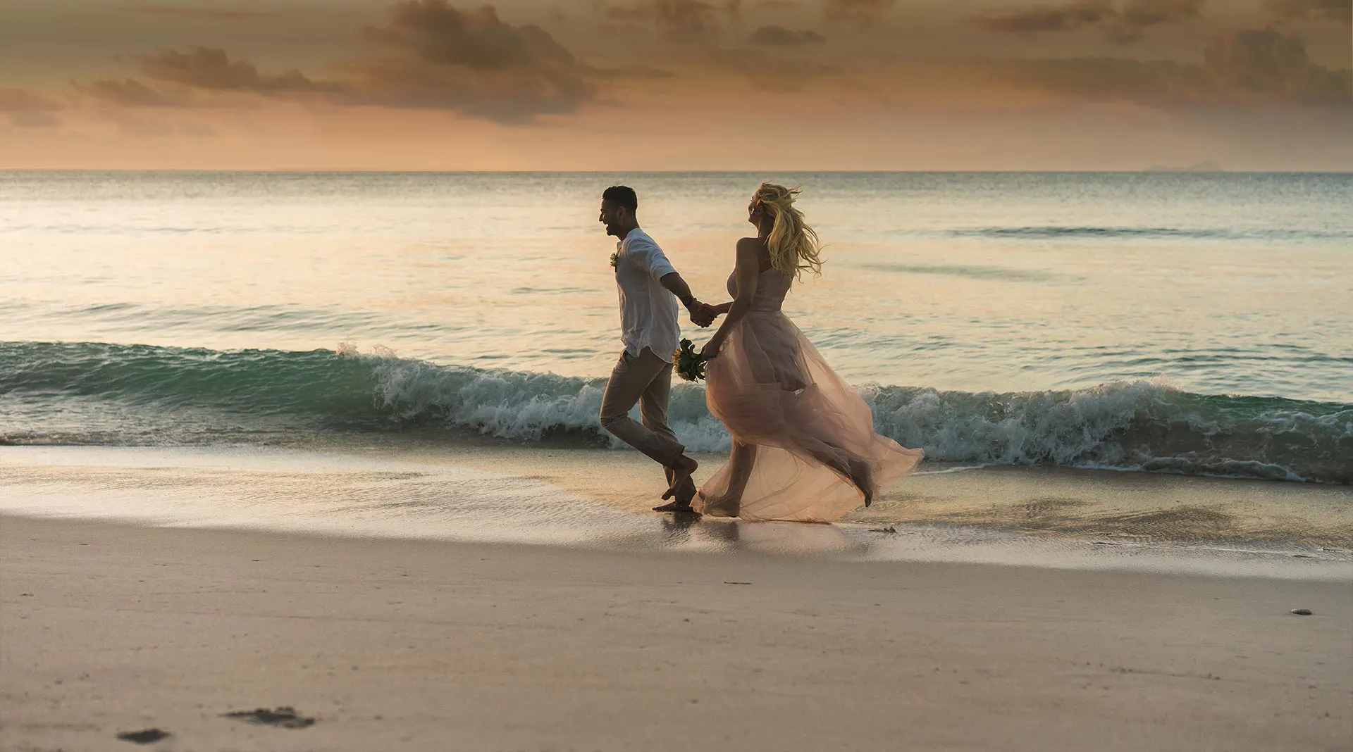 Un couple romantique célébrant son mariage à Zanzibar sur une plage de sable blanc au coucher du soleil.